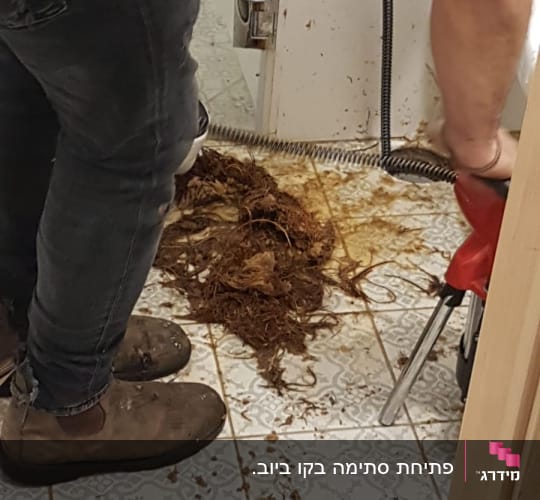 אינסטלטור משתמש במכשיר לפתיחת סתימות בצנרת